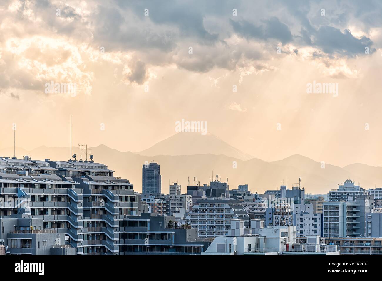 Tramonto a Tokyo, Giappone Shinjuku paesaggio urbano con silhouette vista del Monte Fuji e della luce solare dorata, edifici di appartamenti e montagne con nuvole di pioggia Foto Stock