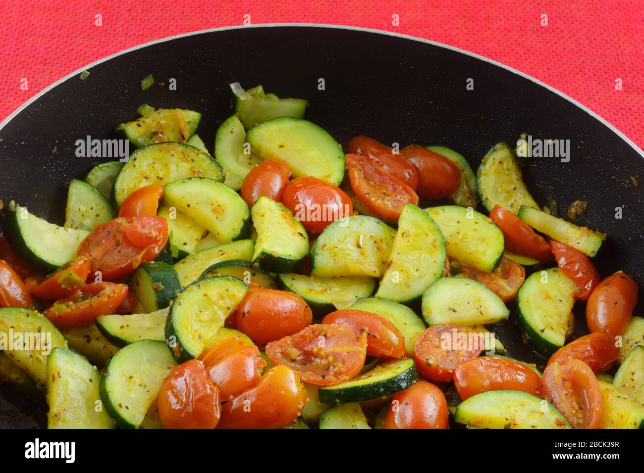 Zucchine a fette e contorno di verdure al pomodoro d'uva saltate in padella Foto Stock