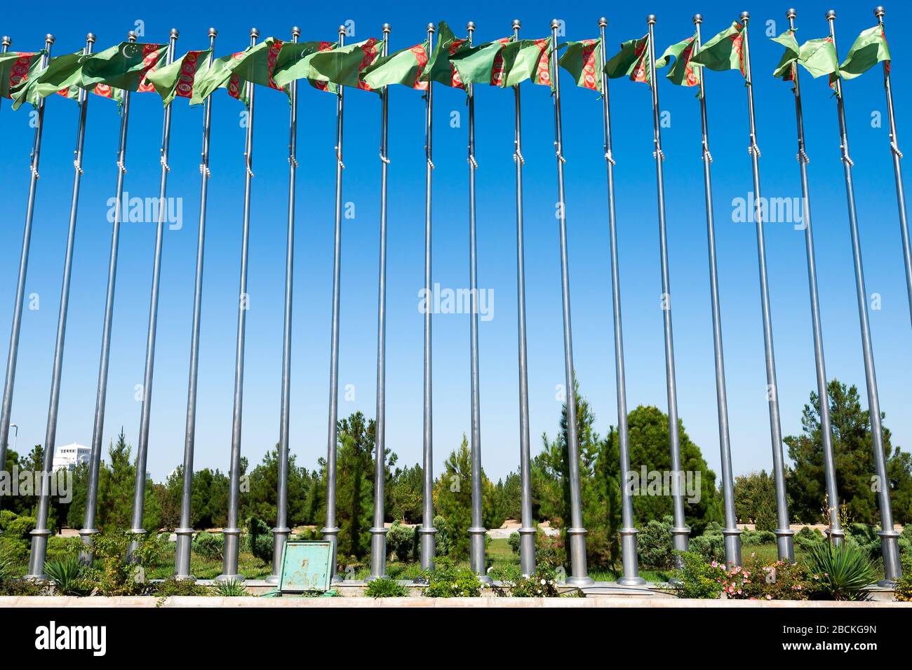 Bandiere turkmenistan multiple nel Parco Independence di Ashgabat, Turkmenistan. Vista laterale della linea di aste di bandiera. Bandiere ondulate. Foto Stock