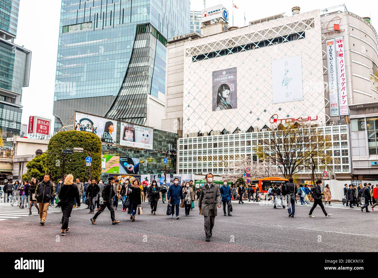 Tokyo, Giappone - 28 marzo 2019: Famoso attraversamento di Shibuya nel centro città con un gruppo di molte persone che camminano indossando maschere durante il giorno Foto Stock