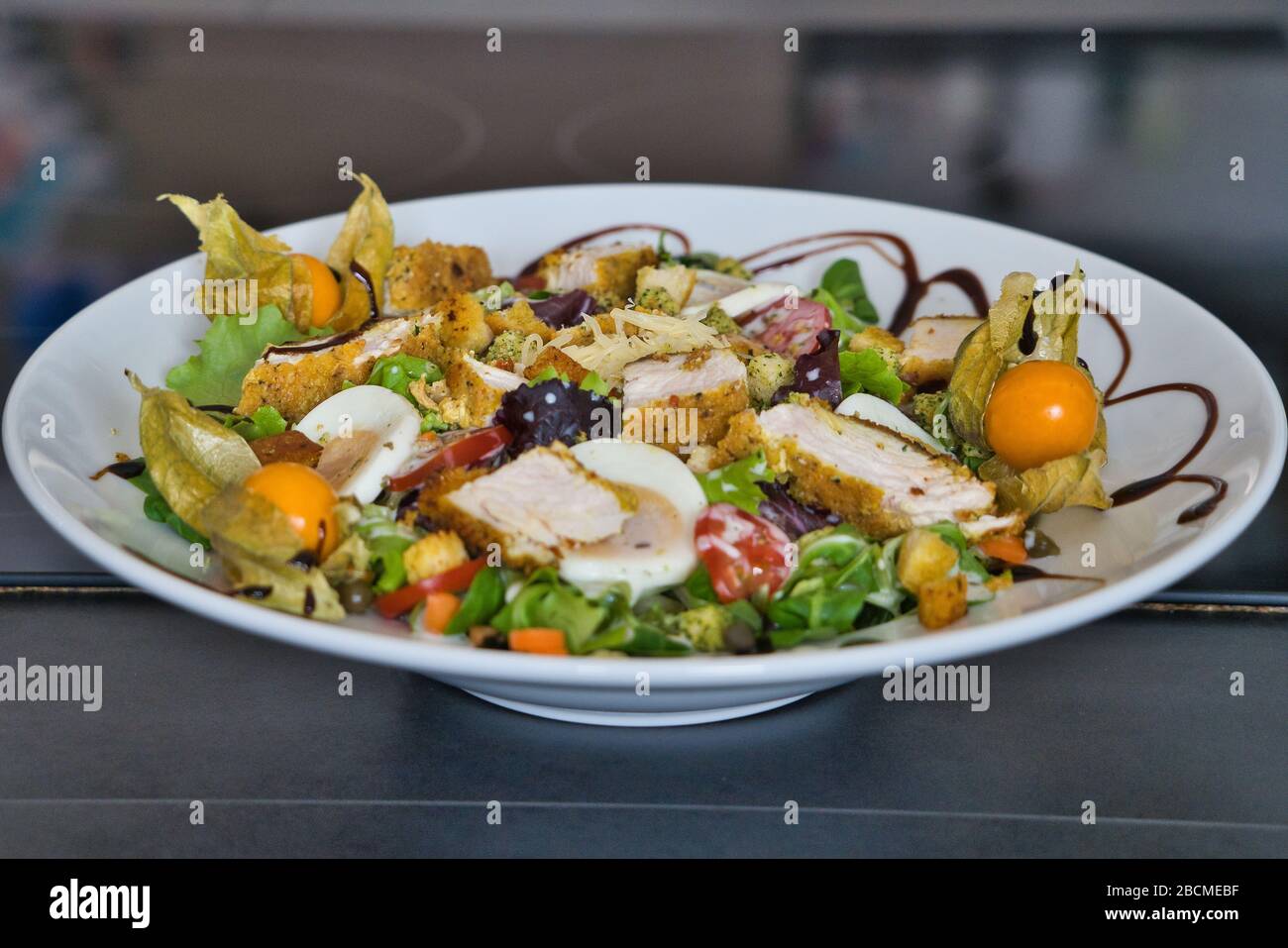 Piatto misto di insalata biologica con strisce di pollo, pomodori, uova, peperone, insalata di campo, aceto balsamico e crostini, immagine del prodotto Foto Stock