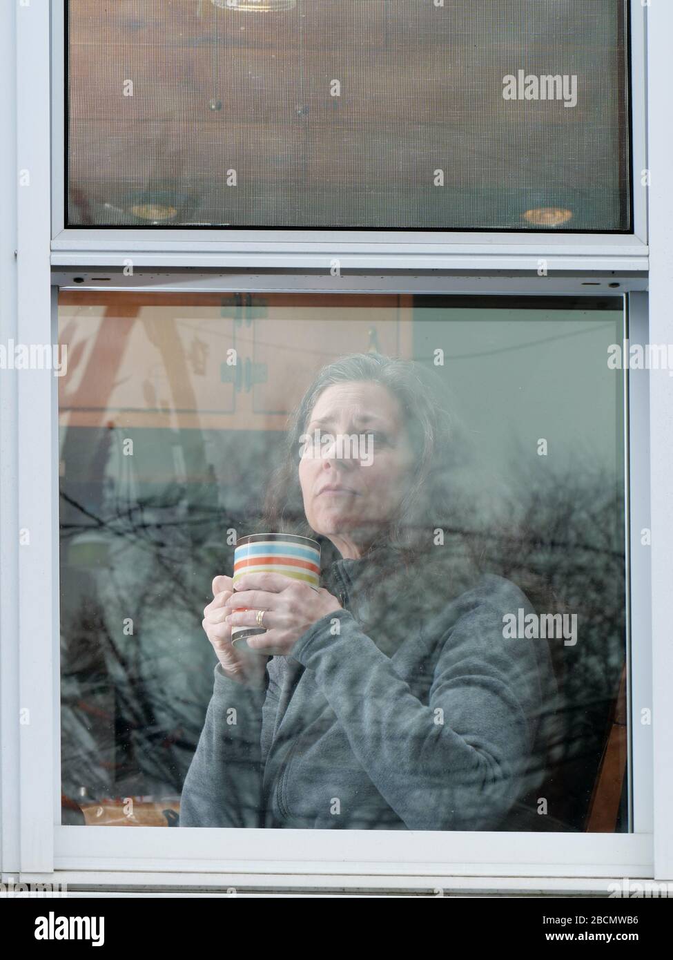 Oak Park, Illinois, Stati Uniti. 4th aprile 2020. Una donna guarda fuori la sua finestra di cucina durante COVID-19 shelter-in-Place ordine. Foto Stock
