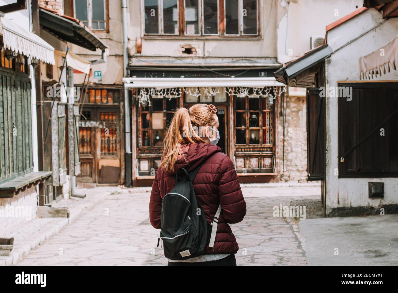 Donna con maschera in piedi da sola in un punto caldo turistico abbandonato bloccato a causa di coronaviri epidemia covid-19 Foto Stock