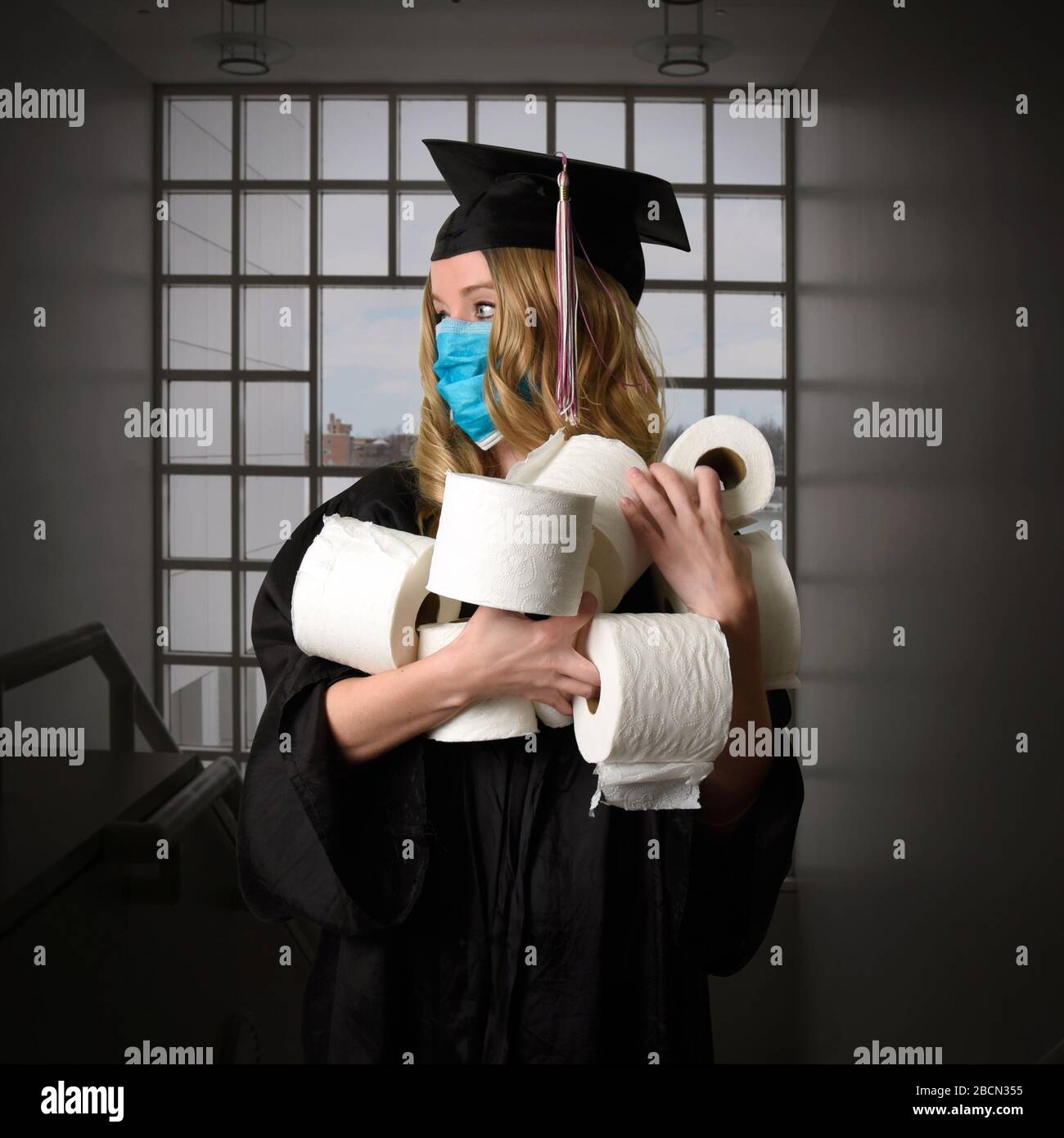 Un laureato senior della classe di 2020 si sta laureando all'interno tenendo carta igienica come un concetto di ritratto umoristico. Foto Stock