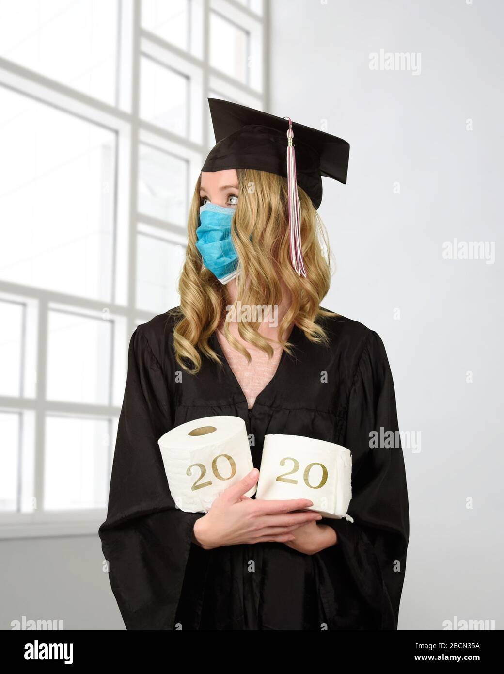 Uno studente indossa un mantello di laurea e un accappatoio di carta igienica per un concetto umoristico della classe di 2020 coronavirus pandemic del covid-10 Foto Stock