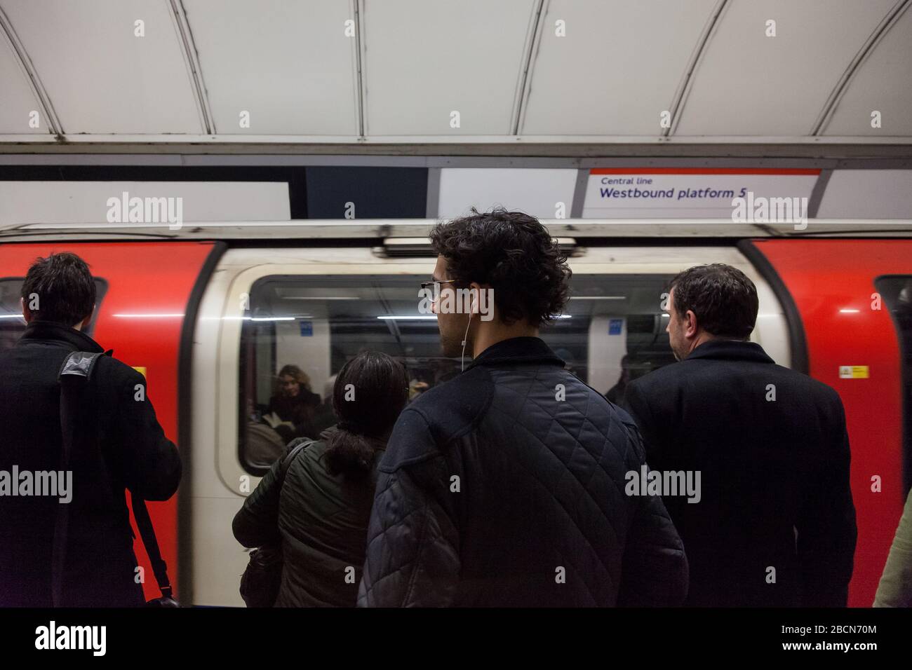La gente aspetta sulla piattaforma di una Central Line London Underground, stazione quando arriva un treno in metropolitana. Londra, Regno Unito. Foto Stock