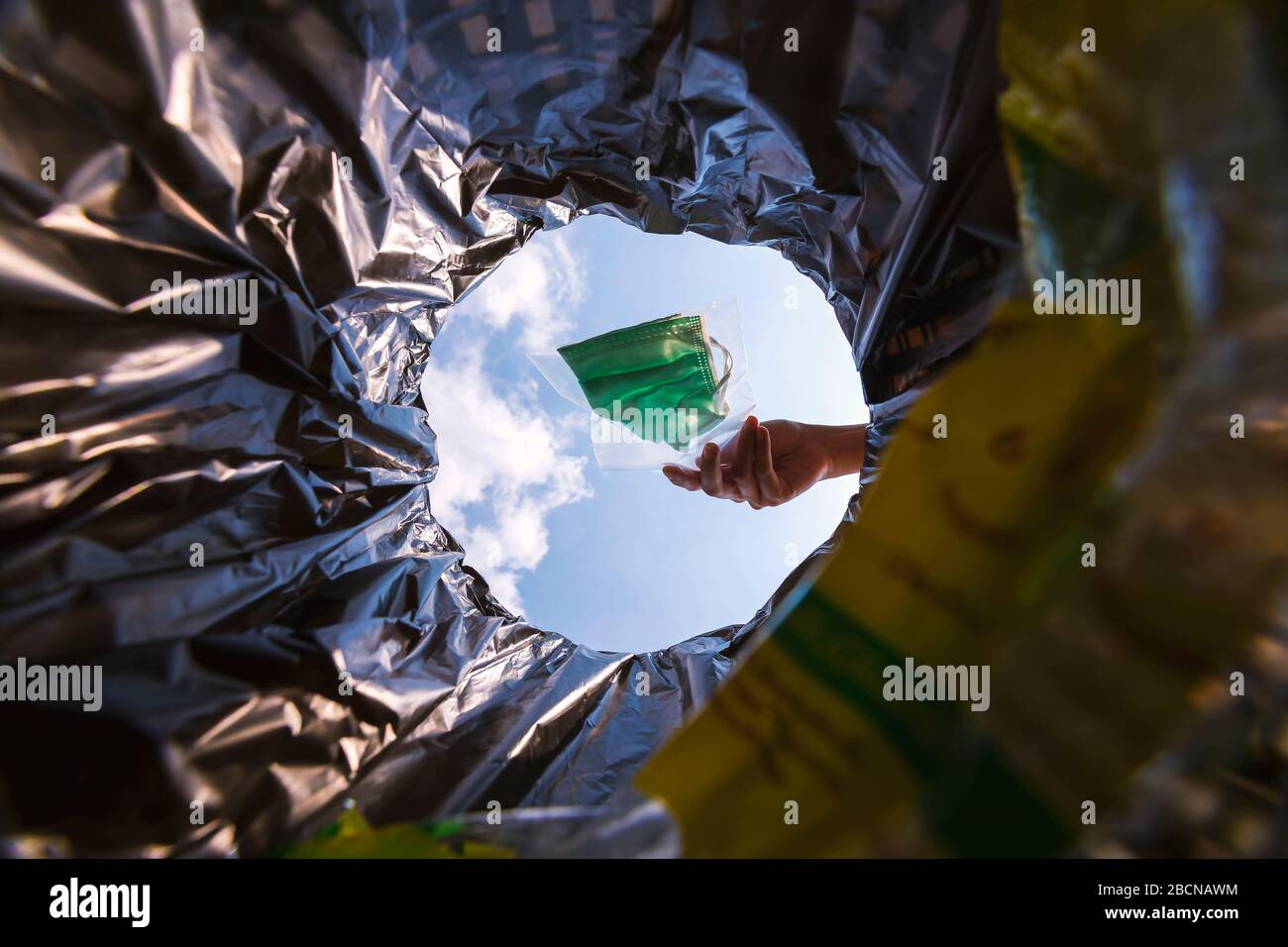 Pacchetto maschera facciale in chiusura lampo prima di gettarlo nel cestino. Con una vista della vite senza fine dall'interno del cestino. Foto Stock