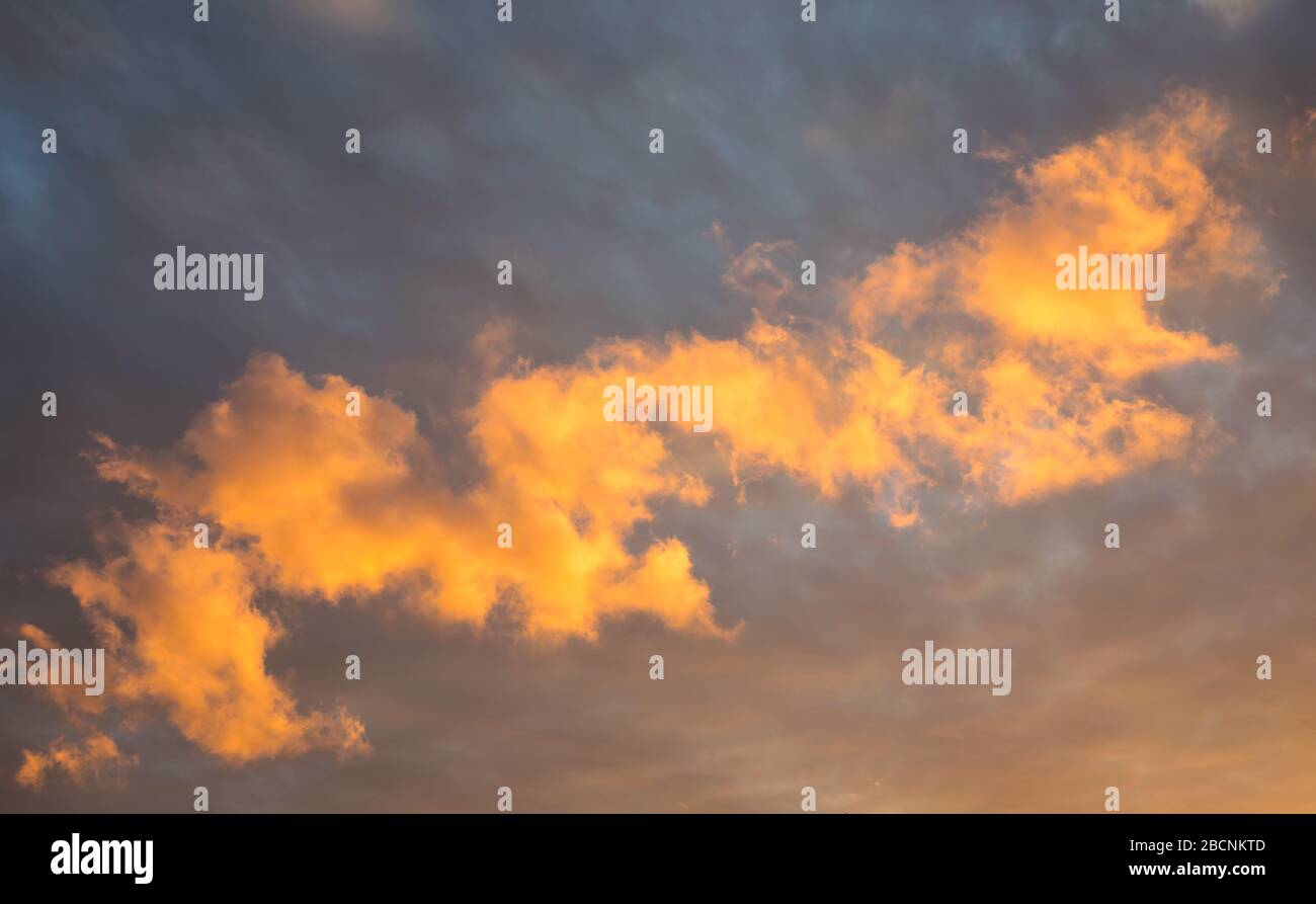 Le nuvole basse sono colorate illuminate dalla luce del sole che tramonta mentre si avvicina il fronte del tempo. Adatto come sfondo o carta da parati. Foto Stock