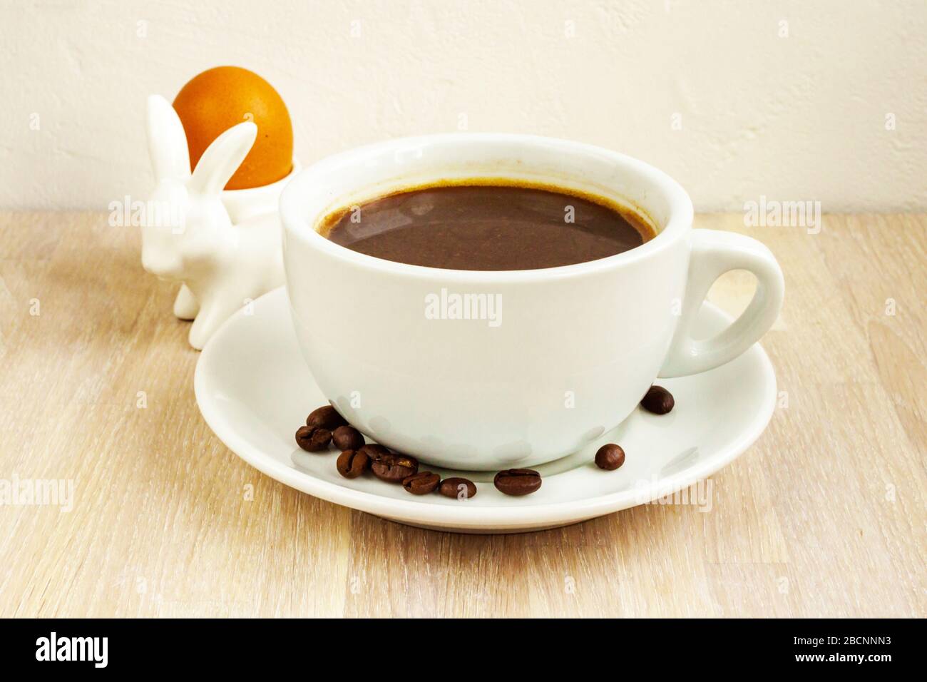 Tazza da caffè, piattino, fagioli, portauova di coniglio. Colazione di Pasqua Foto Stock