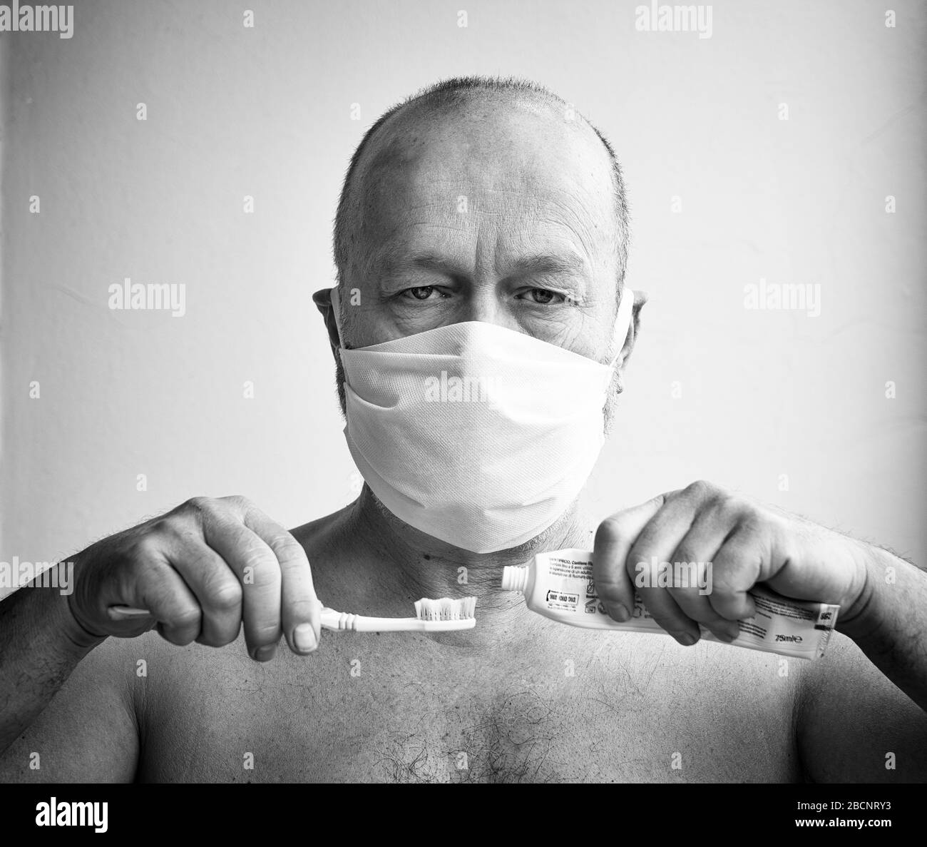 un uomo gli spazzola i denti con una maschera protettiva durante il periodo del coronavirus Foto Stock