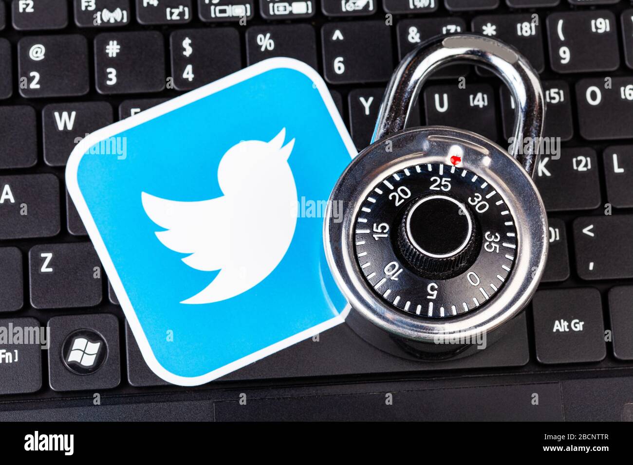Account Twitter sicurezza password semplice concetto astratto. Il logo del servizio Twitter e un lucchetto con codice metallico, con lucchetto posizionato su una tastiera nera per computer portatili Foto Stock