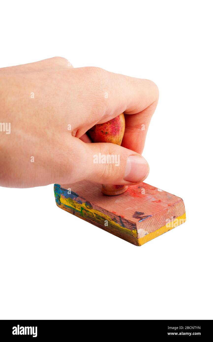 Semplice francobollo in legno tenuto in mano, timbro gesto primo piano. Mano che tiene un vecchio timbro di gomma artsy sporco usurato fatto di legno spruzzato, coperto di vernice Foto Stock
