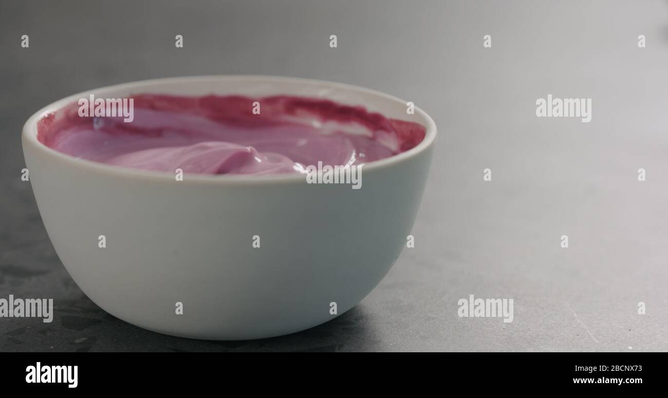 yogurt bilberry in recipiente bianco su superficie in cemento Foto Stock