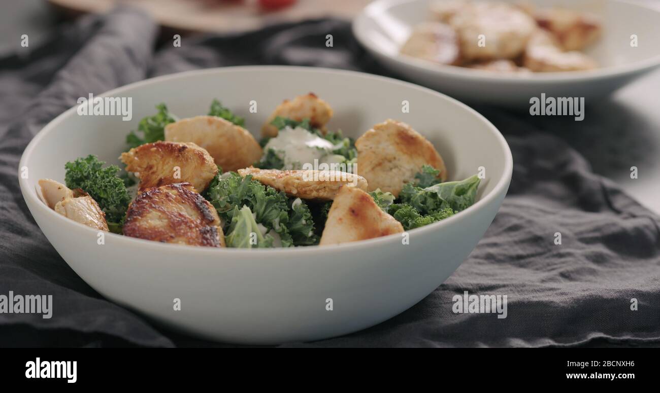 preparare l'insalata caesar con kale e tacchino in una ciotola bianca, aggiungere il tacchino Foto Stock