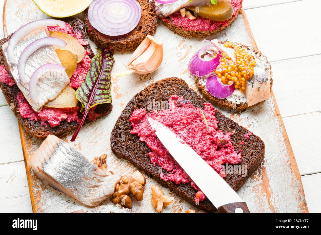 Piccoli panini o bruschette con aringhe salate e barbabietole. Panino aperto con aringhe salate Foto Stock