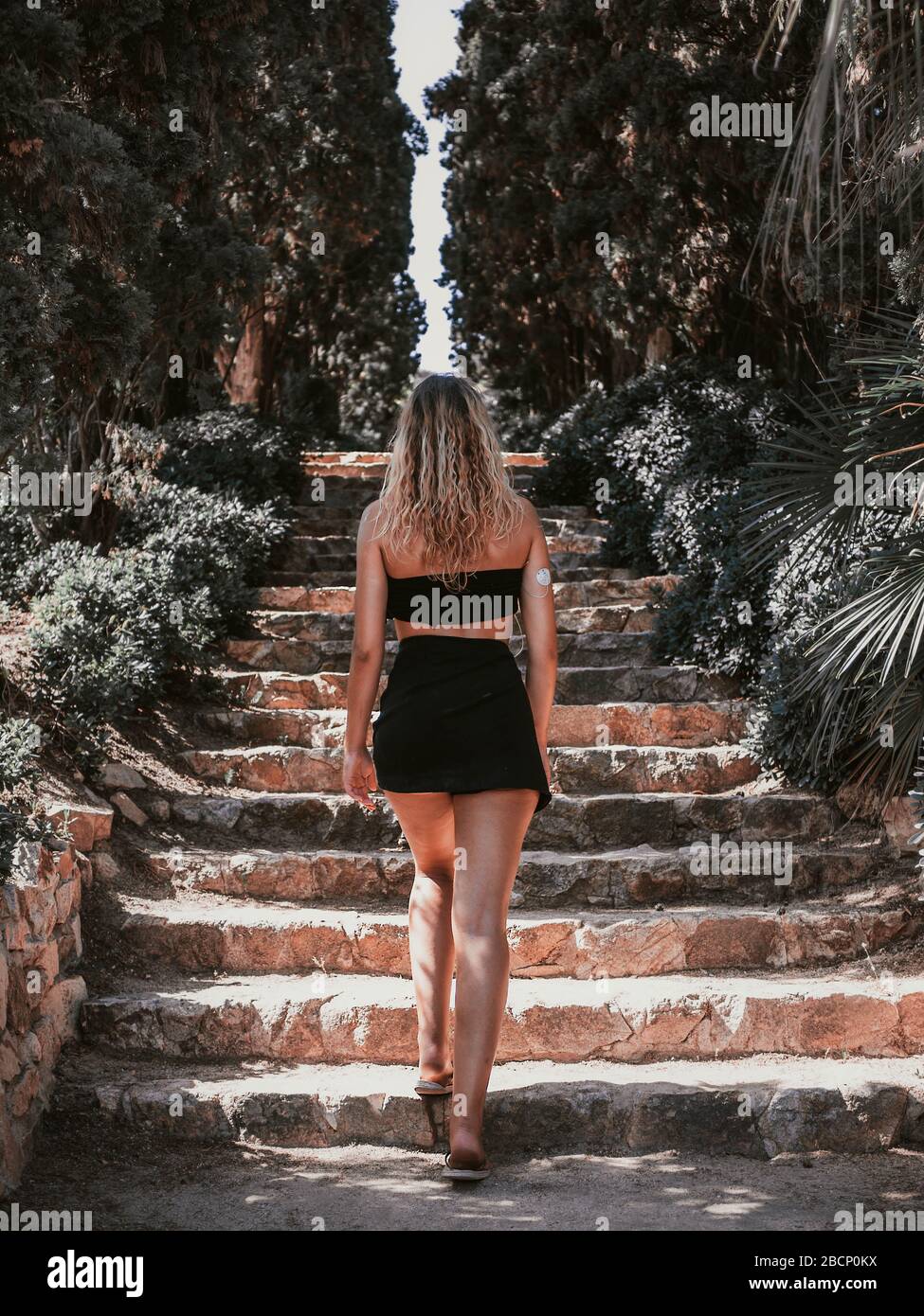 giovane donna bionda che sale una scala in mezzo alla natura in una giornata estiva soleggiato con vestiti piccoli Foto stock Alamy