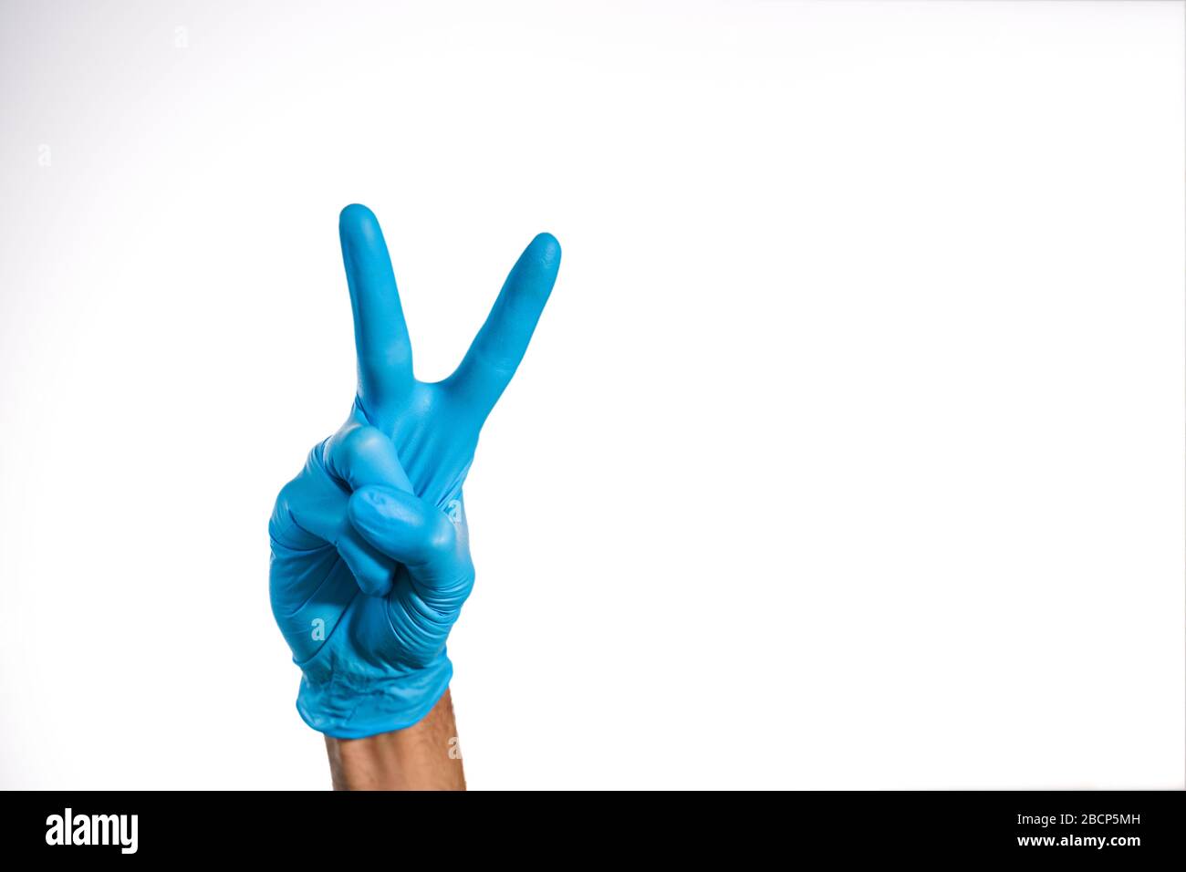 Mano medica con guanto blu che esegue il gesto V. Foto Stock