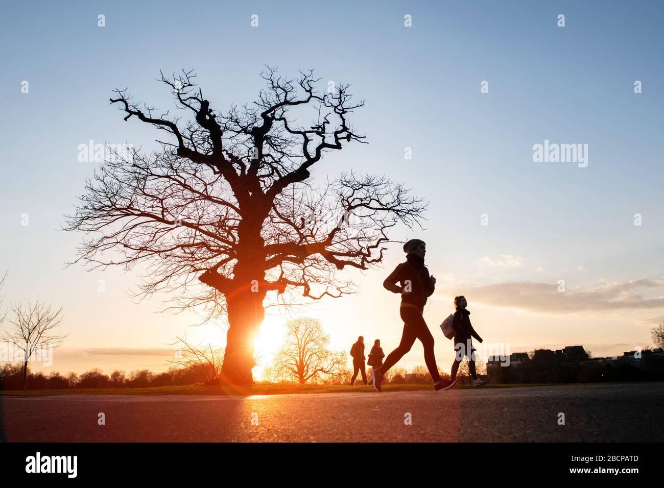 Due ragazze che corrono e tengono in forma (sotto blocco per Corona virus Covid 19 restrizioni) sotto un drammatico tramonto nel marzo 2020 Foto Stock Due ragazze che corrono e tengono in forma (sotto blocco per Corona virus Covid 19 restrizioni) sotto un drammatico tramonto nel marzo 2020 Foto Stock