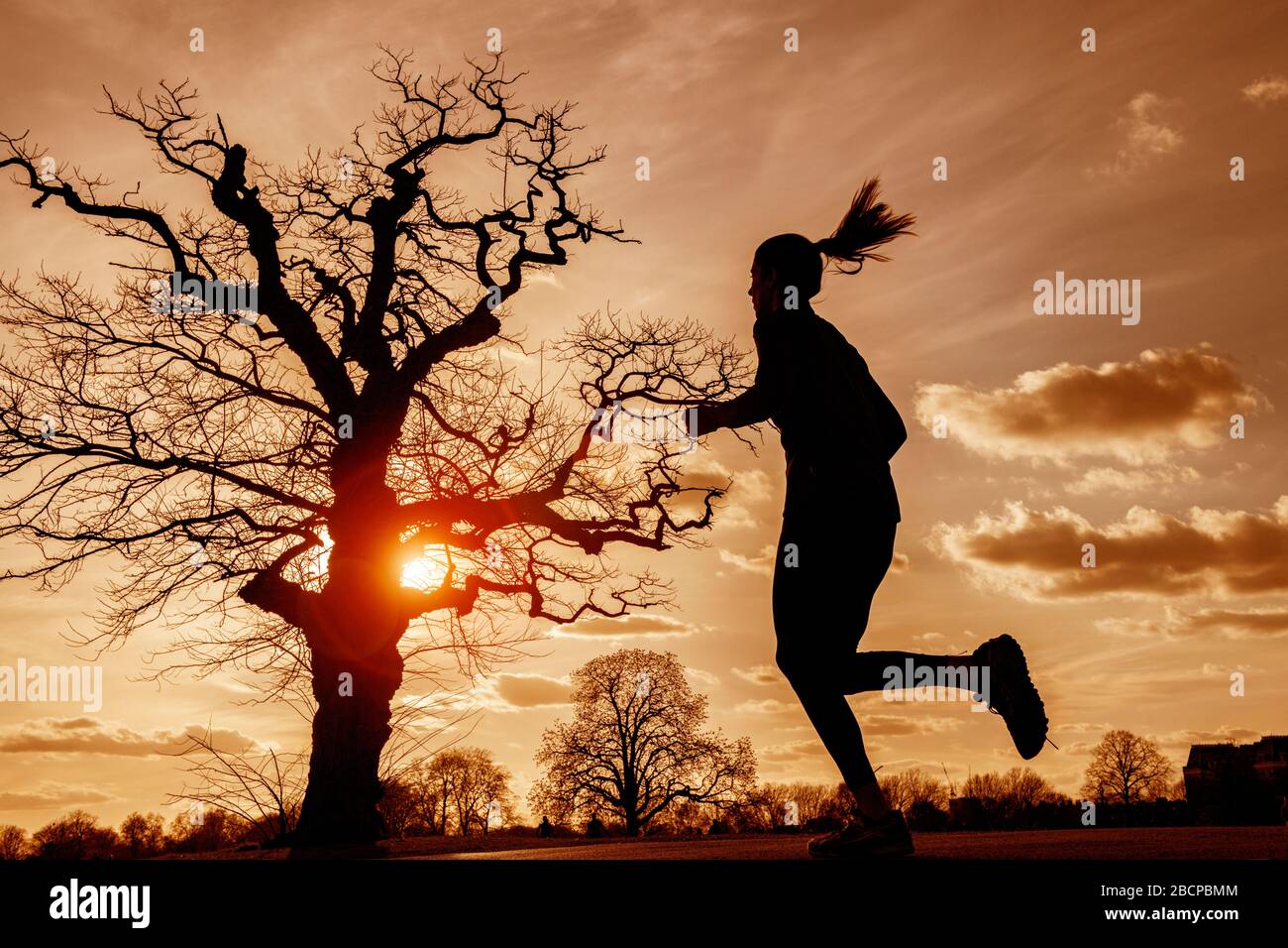 Running e mantenersi in forma (sotto blocco per Corona virus Covid 19 restrizioni) sotto un drammatico tramonto nel marzo 2020 Foto Stock Running e mantenersi in forma (sotto blocco per Corona virus Covid 19 restrizioni) sotto un drammatico tramonto nel marzo 2020 Foto Stock
