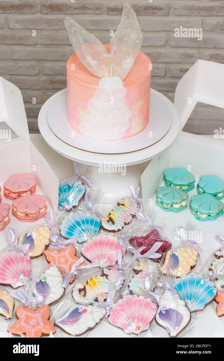 Caramelle a tema Mermaid con torta, cupcake, macaroon e biscotti. Macaroni a forma di conchiglia di mare con perle. Torta rosa con coda di mermaid al caramello. Foto Stock