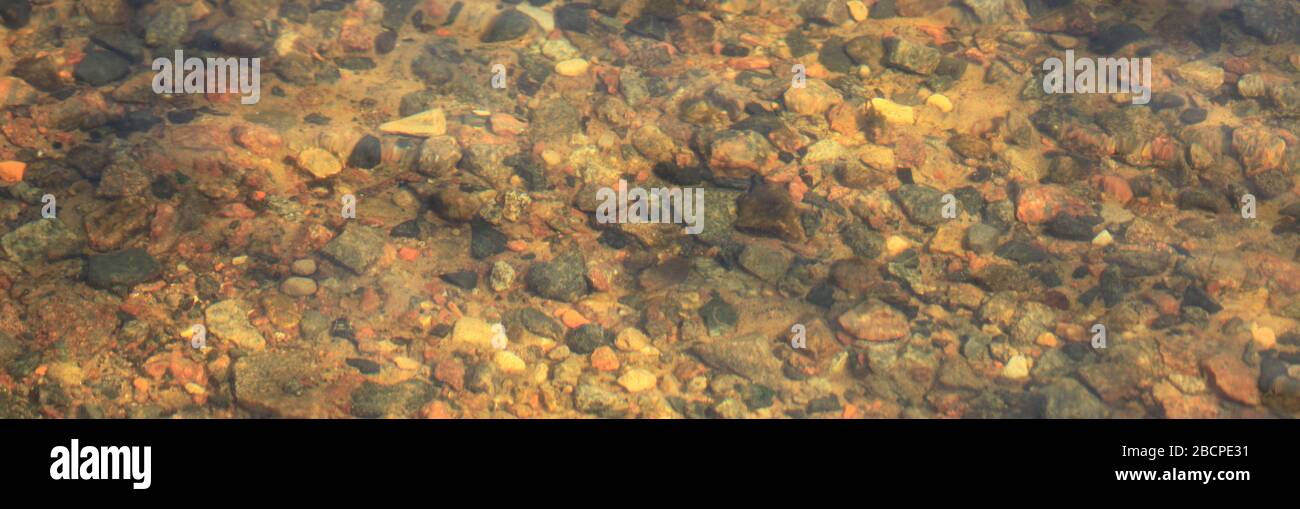 La struttura del fondo del fiume con ciottoli di granito attraverso l'acqua di sorgente limpida. Pitture astratte e schizzi della natura. Tavolozza surrealistica Foto Stock