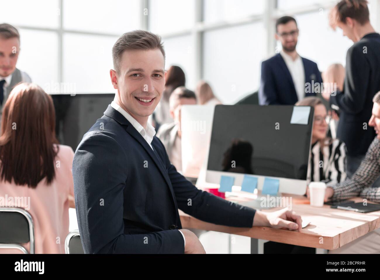 Giovane uomo d'affari seduto alla sua scrivania e guardando la macchina fotografica Foto Stock