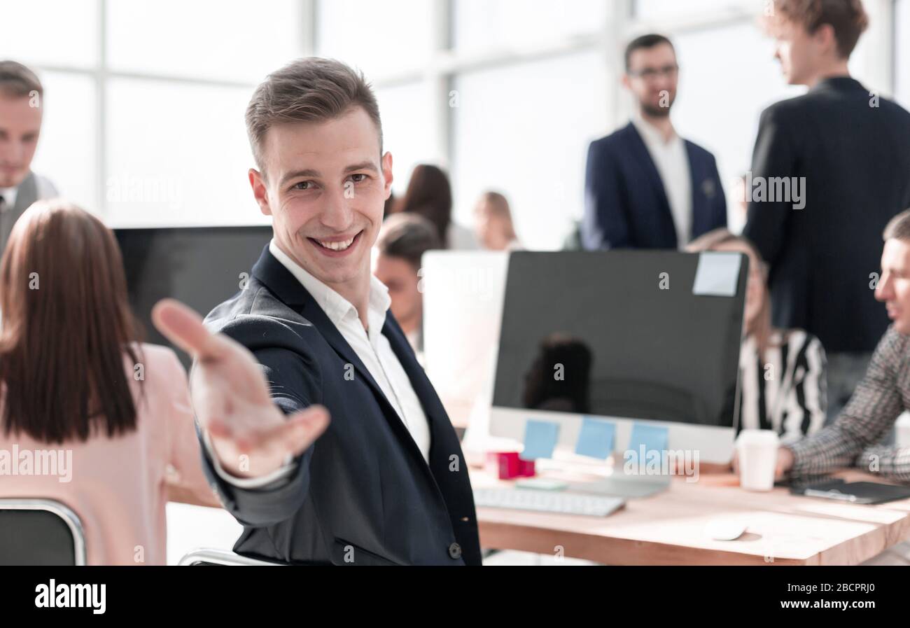 Giovane uomo d'affari cordiale seduto alla sua scrivania Foto Stock