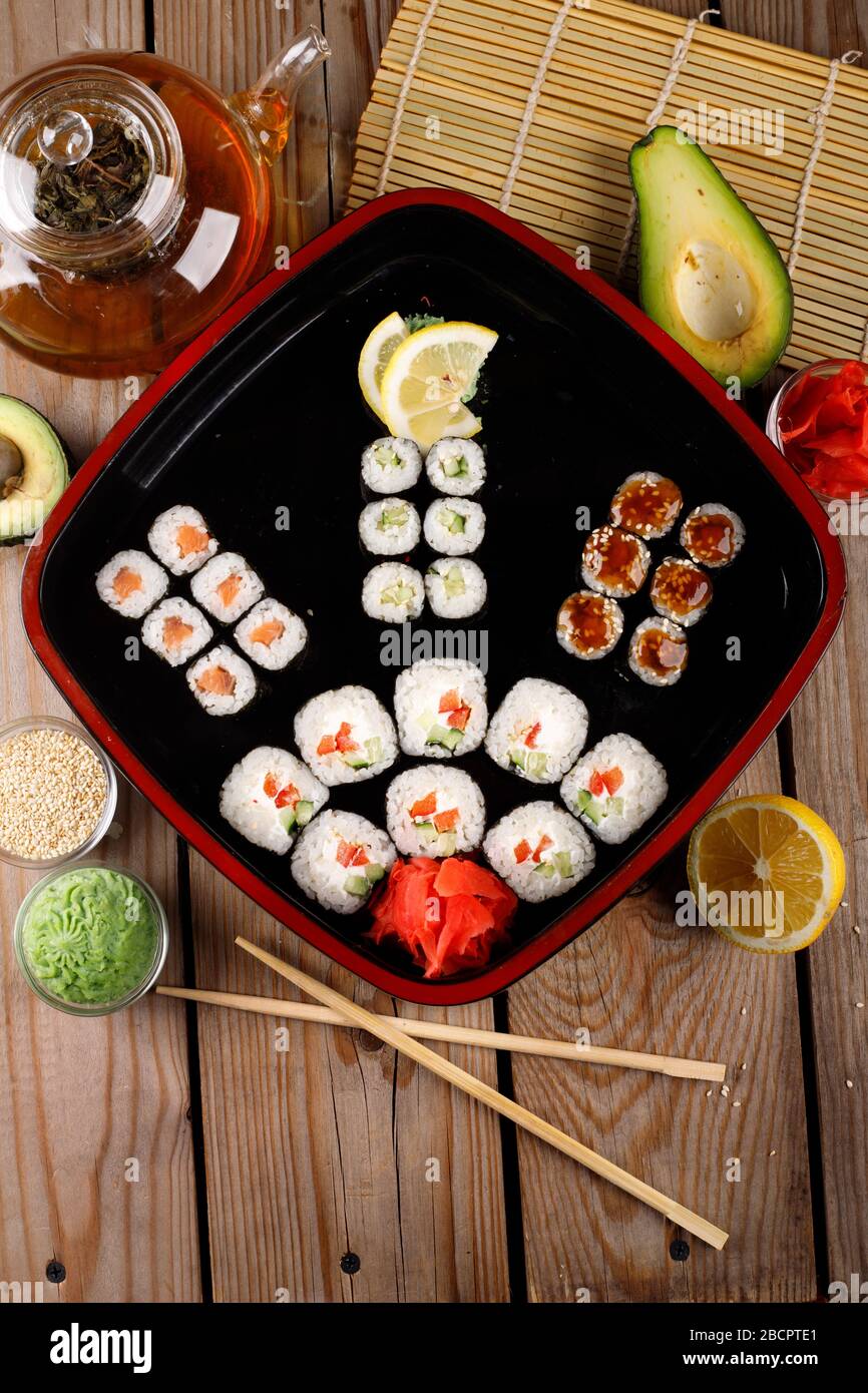 grande set di sushi colorato in un piatto quadrato. su uno sfondo di legno Foto Stock
