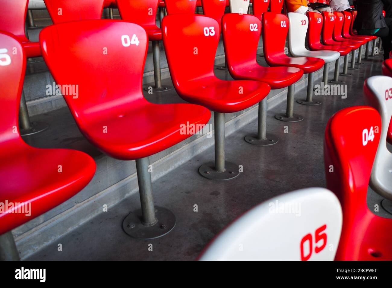 File di sedili in plastica in uno stadio sportivo. I sedili sono rossi e bianchi. Foto Stock