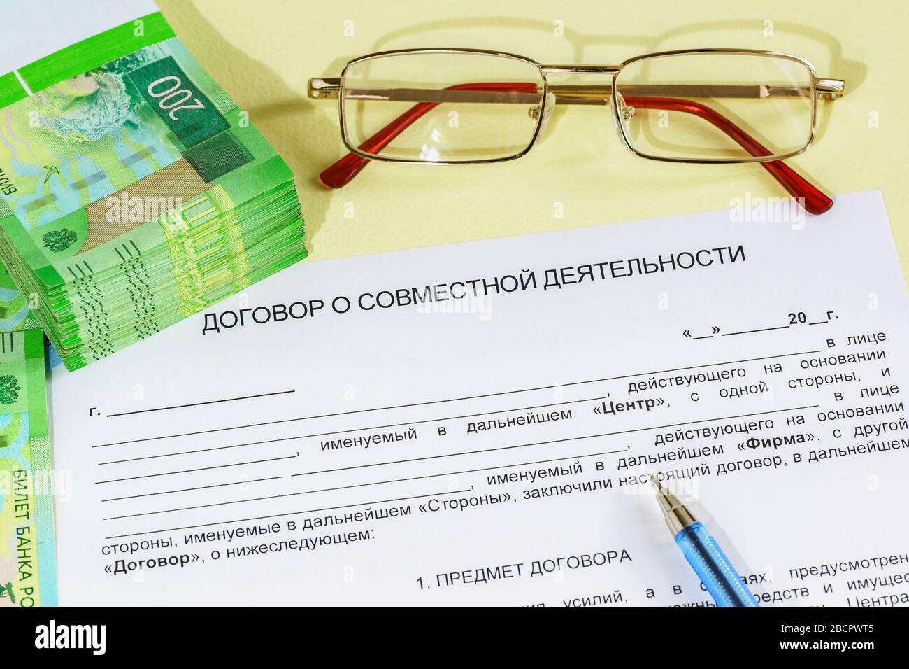 Registrazione di un accordo di attività comune. Una forma, una penna, occhiali e una bacchetta di denaro russo sul tavolo. L'iscrizione in russo 'accordo su Foto Stock