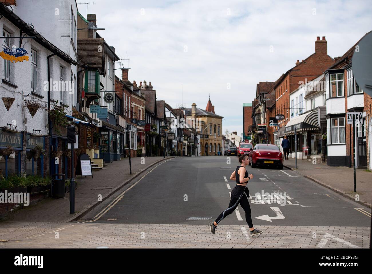 Una donna che corre in una Stratford-upon-Avon quasi deserta nel Warwickshire, mentre il Regno Unito continua a bloccarsi per contribuire a frenare la diffusione del coronavirus. Foto Stock