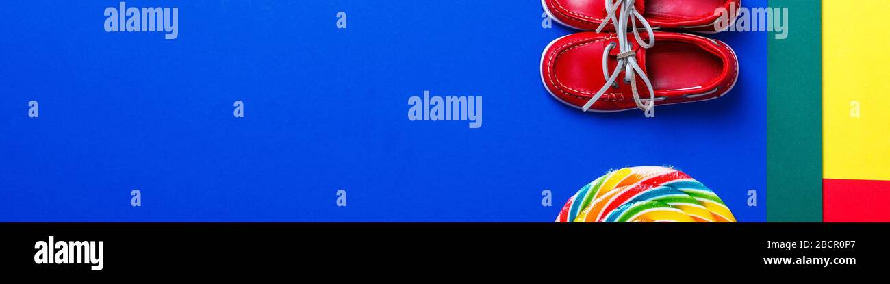 Banner di piccole scarpe rosse barca vicino grande lollipop multicolore e  corda su sfondo colorato Foto stock - Alamy