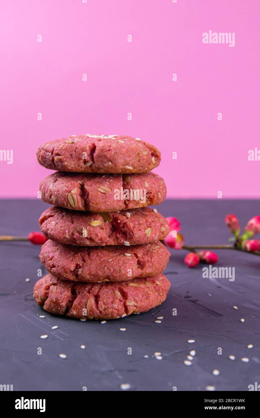 Una pila di biscotti alla barbabietola con farinata d'avena si trova su un  tavolo nero con un ramo fiorito con fiori di rosa Foto stock - Alamy