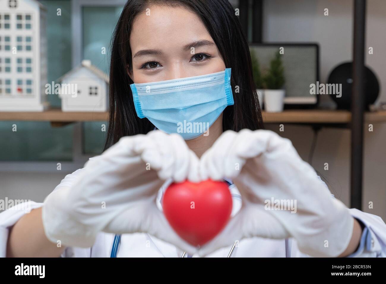 Sorridente femmina medico tenuta forma del cuore in ospedale. Foto Stock