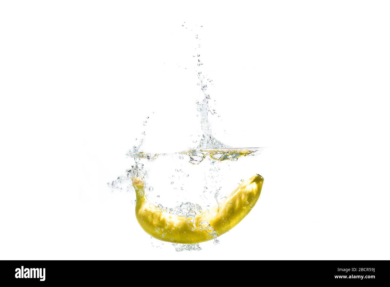 una banana che cade in acqua su uno sfondo bianco con spruzzi. Foto Stock