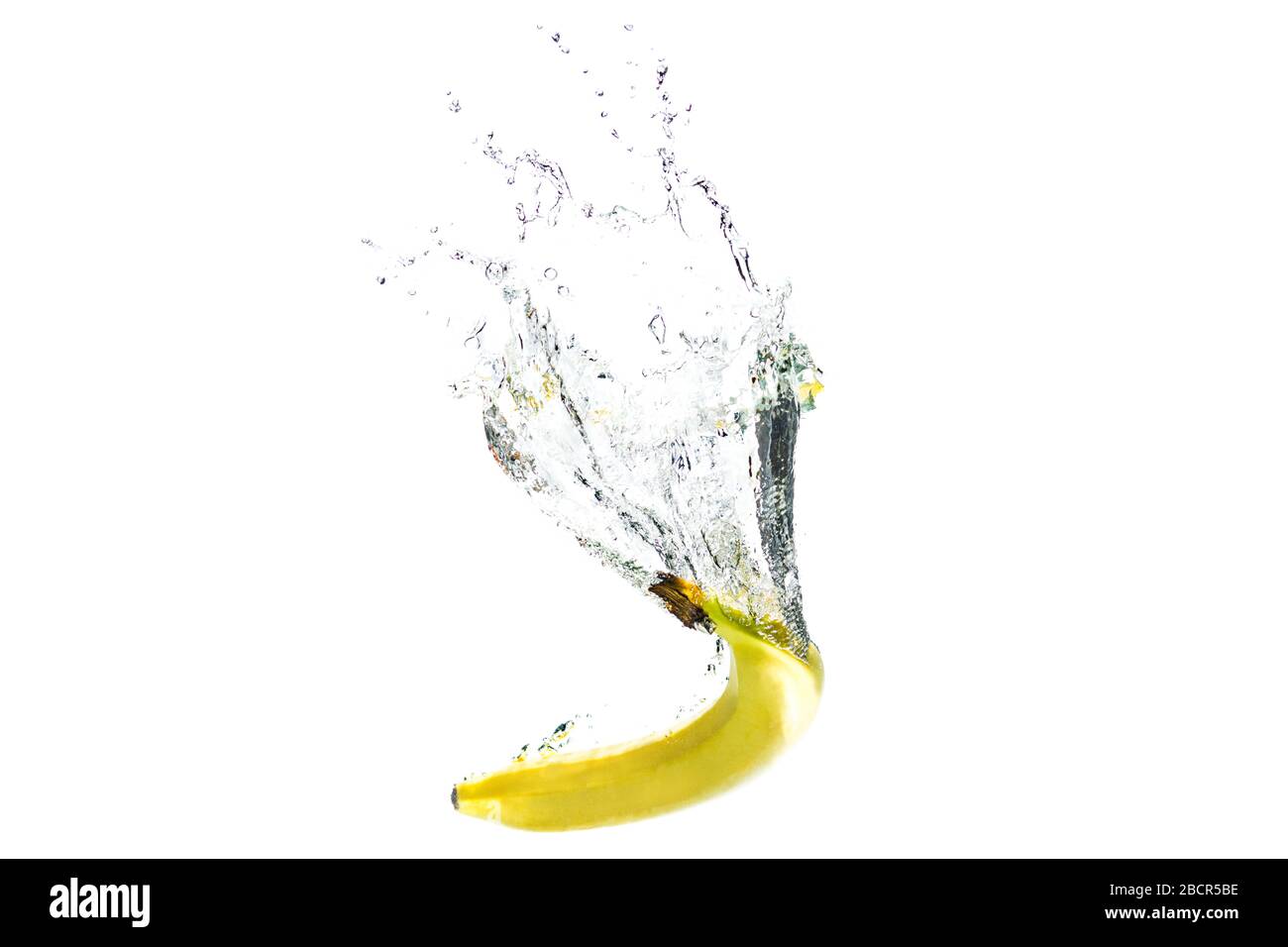 una banana che cade in acqua su uno sfondo bianco con spruzzi. Foto Stock