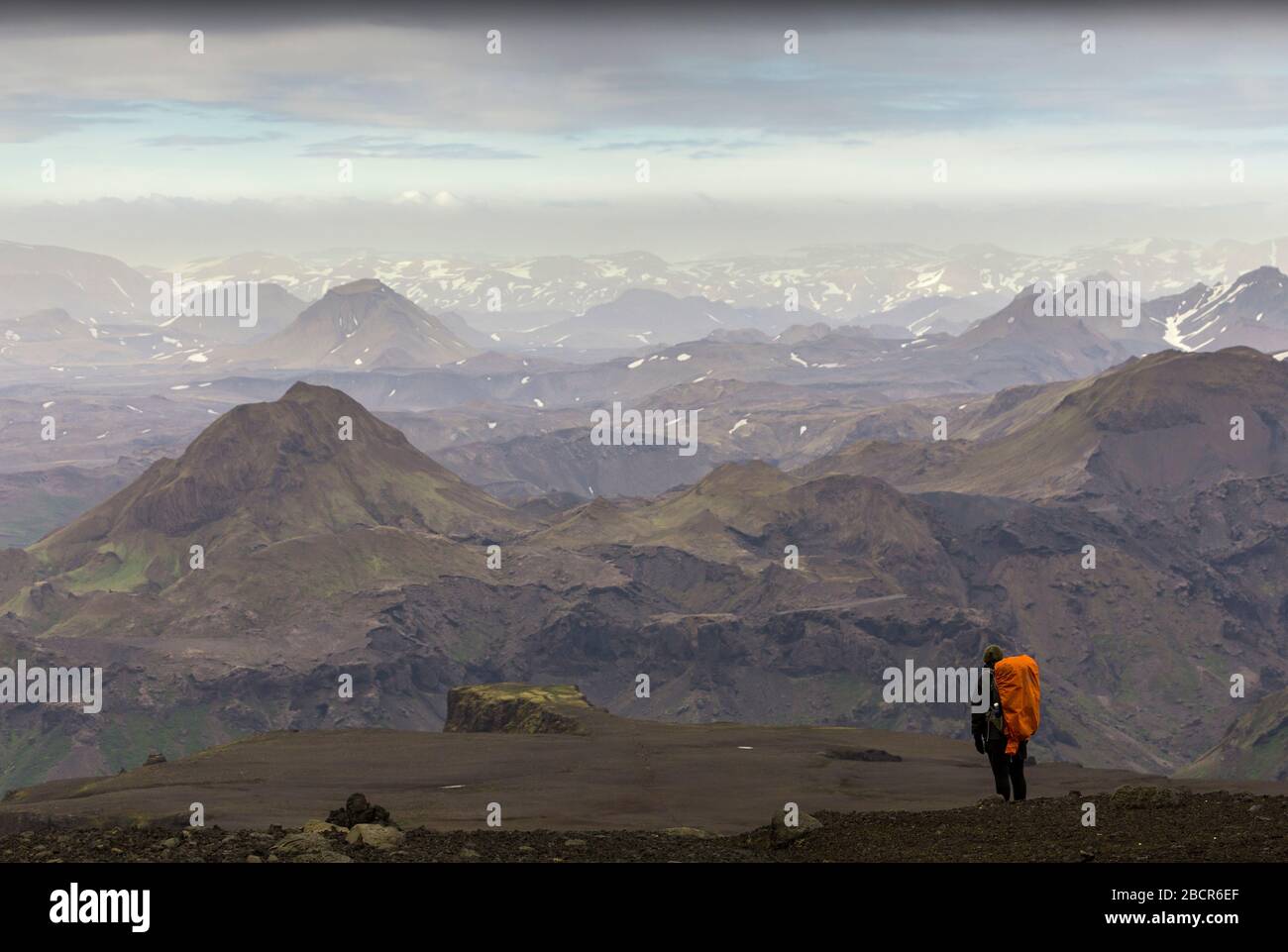 Escursionista femminile che guarda un paesaggio montuoso durante l'escursione a Fimmvörðuháls, Islanda Foto Stock