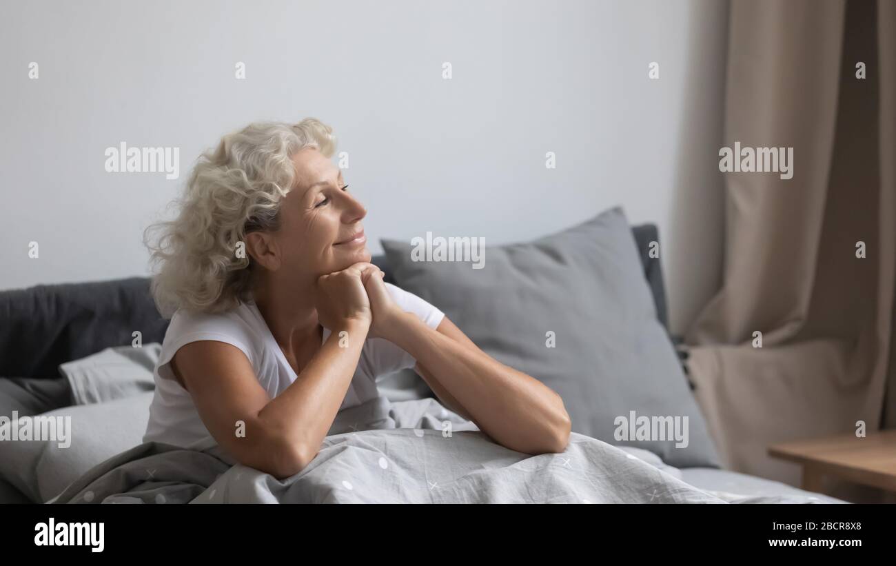 Tranquilla donna di mezza età accogliente nuovo giorno in camera da letto. Foto Stock