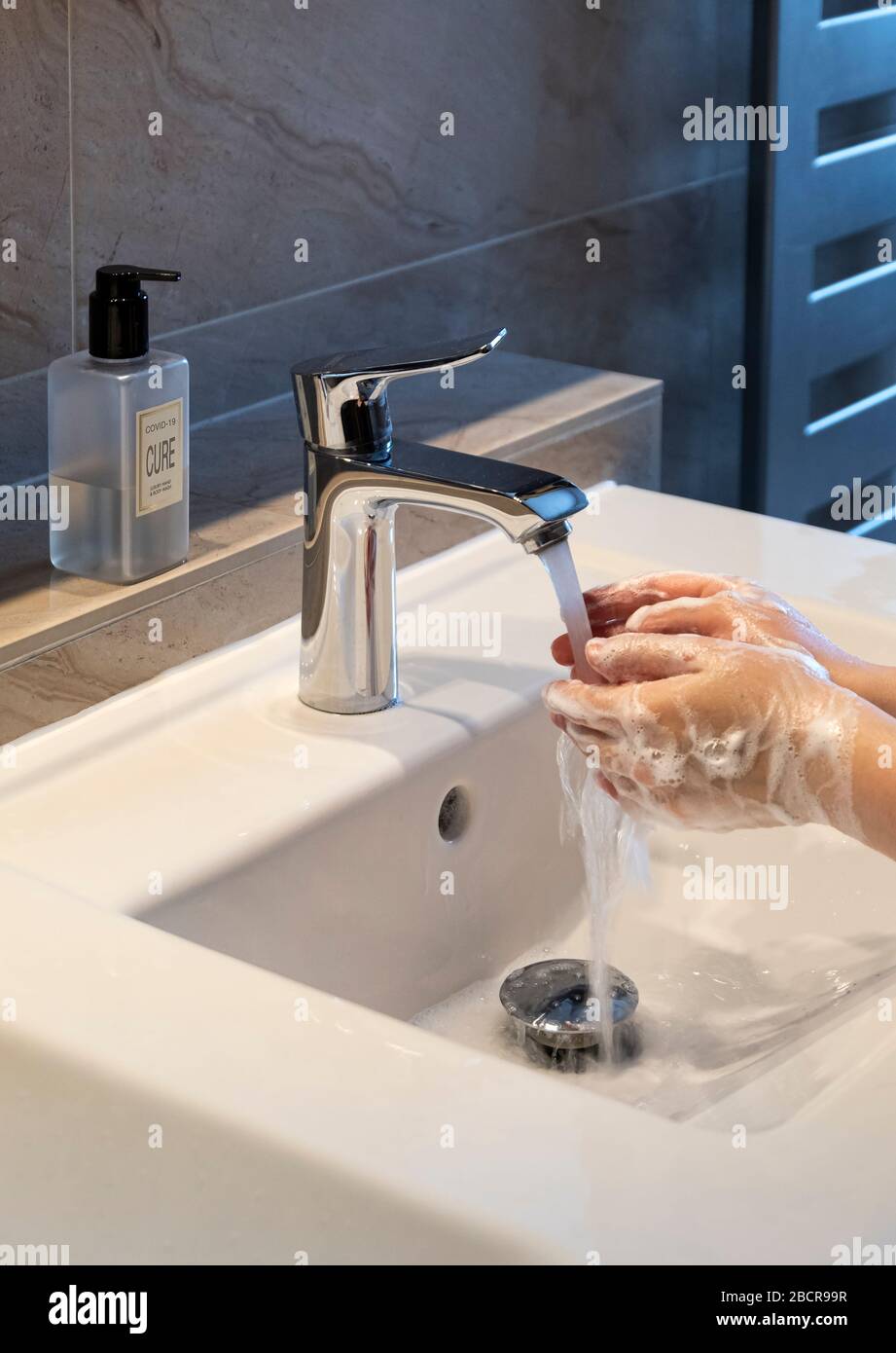 Covid-19 o Coronavirus con cura scritta su sapone Dispenser per ridurre la contaminazione da lavaggio mani in bagno moderno Foto Stock