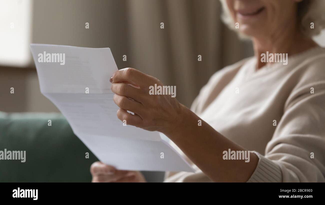 Chiudere le mani delle donne grinze che trattengono il documento di carta. Foto Stock