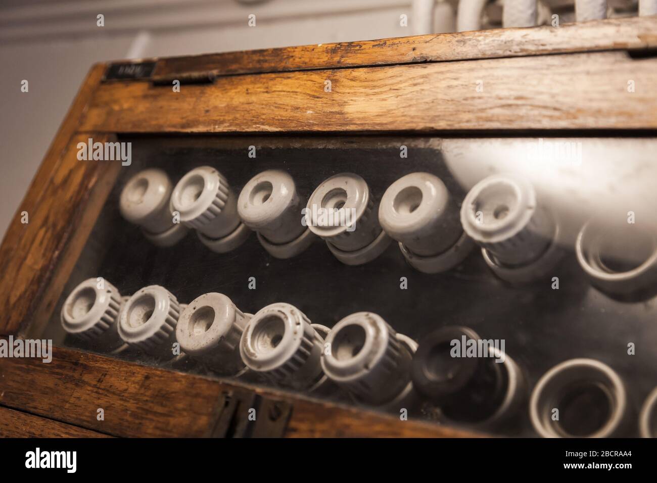 Fusibili elettrici vintage montati su un pannello scuro in una custodia di legno Foto Stock