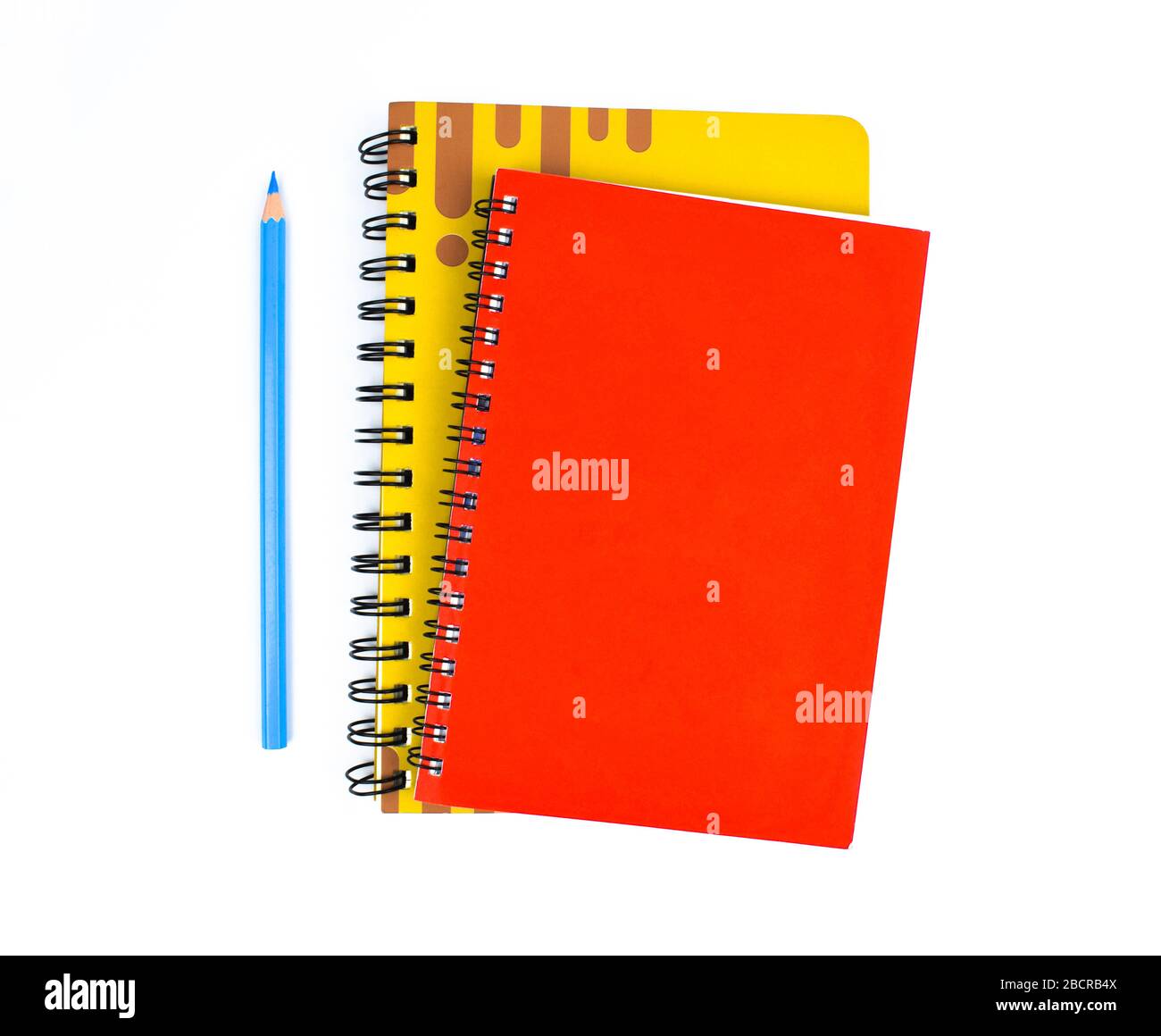 due diari di colore rosso e giallo si trovano accanto ad una matita di colore azzurro su uno sfondo bianco Foto Stock