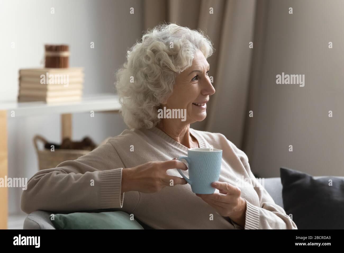 Calma donna matura sognare del futuro con una tazza di tè. Foto Stock