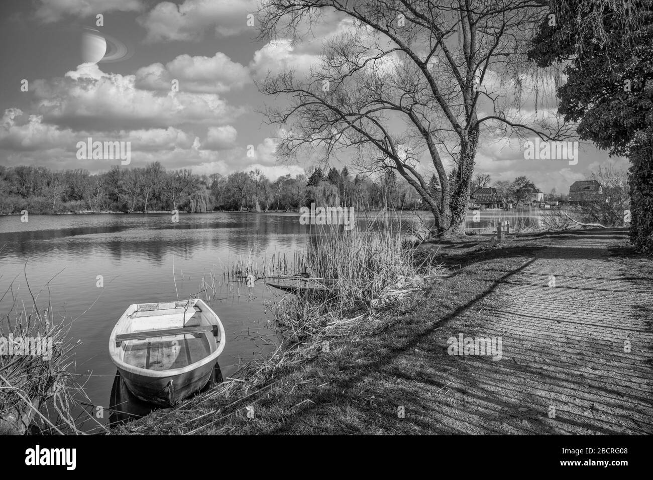 una barca a remi è ormeggiata sulla riva di un piccolo lago con il bel tempo Foto Stock
