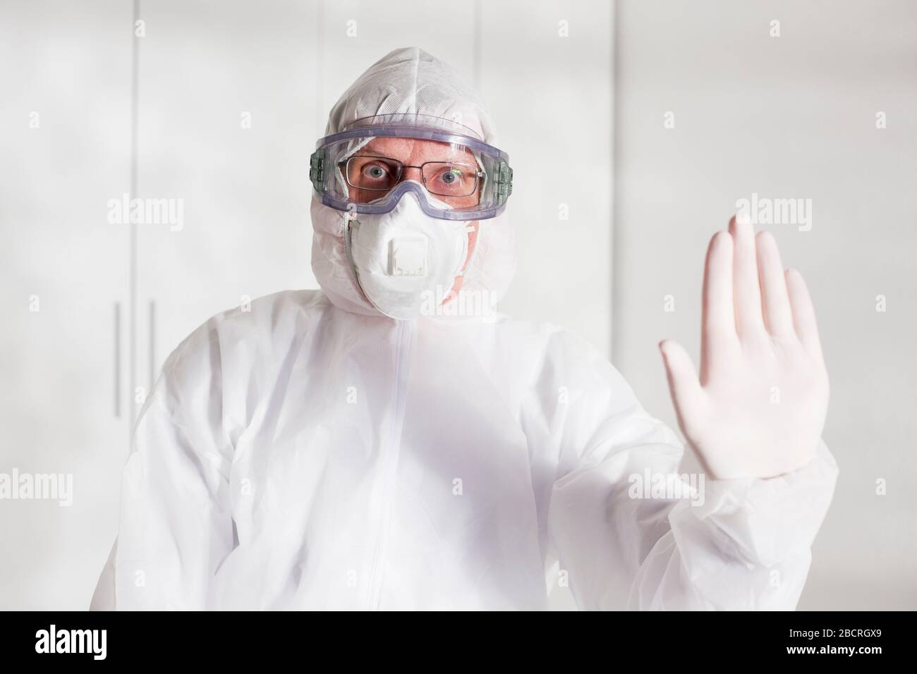 Medico con indumenti protettivi a causa di covid-19 gesturing stop - sfondo bianco Foto Stock