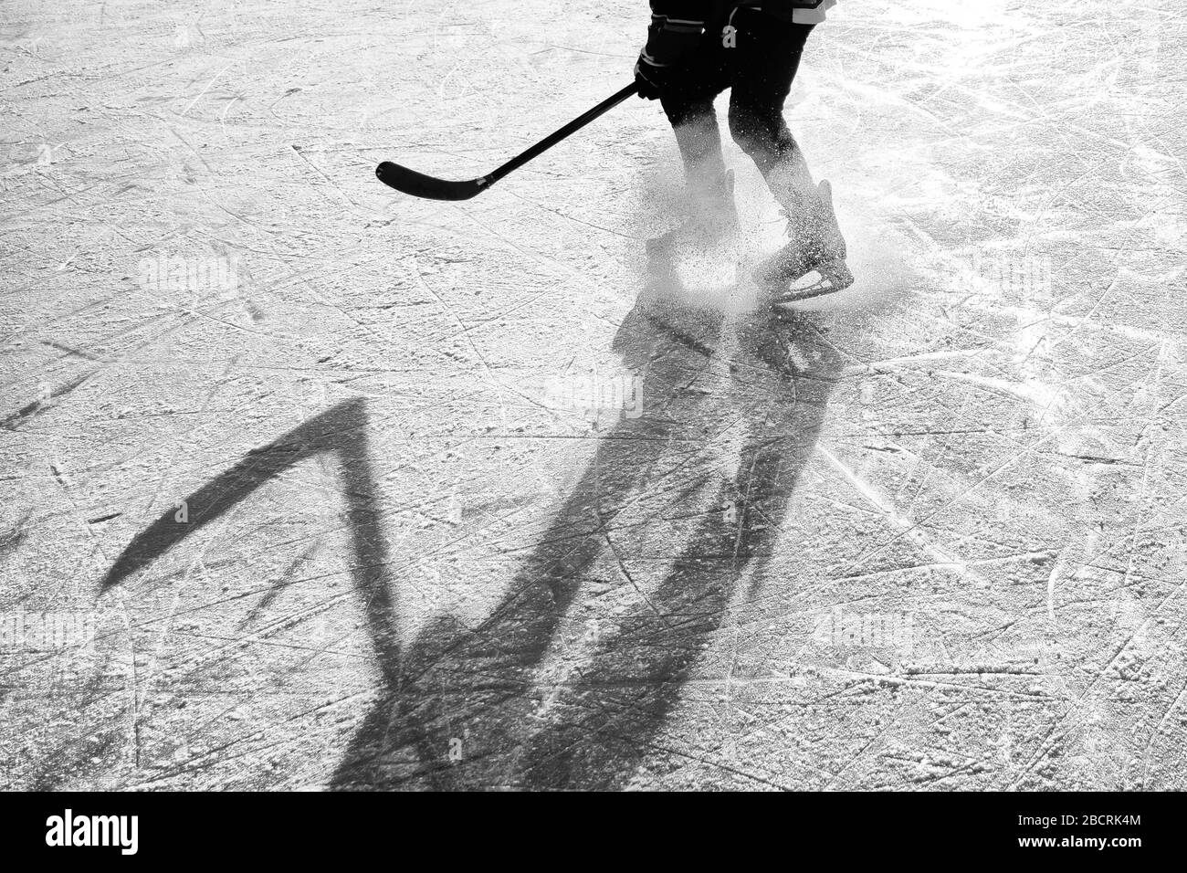 Silhouette di un giovane giocatore di hockey che si diverte sul ghiaccio naturale. Carta da parati originale, sportiva, invernale Foto Stock