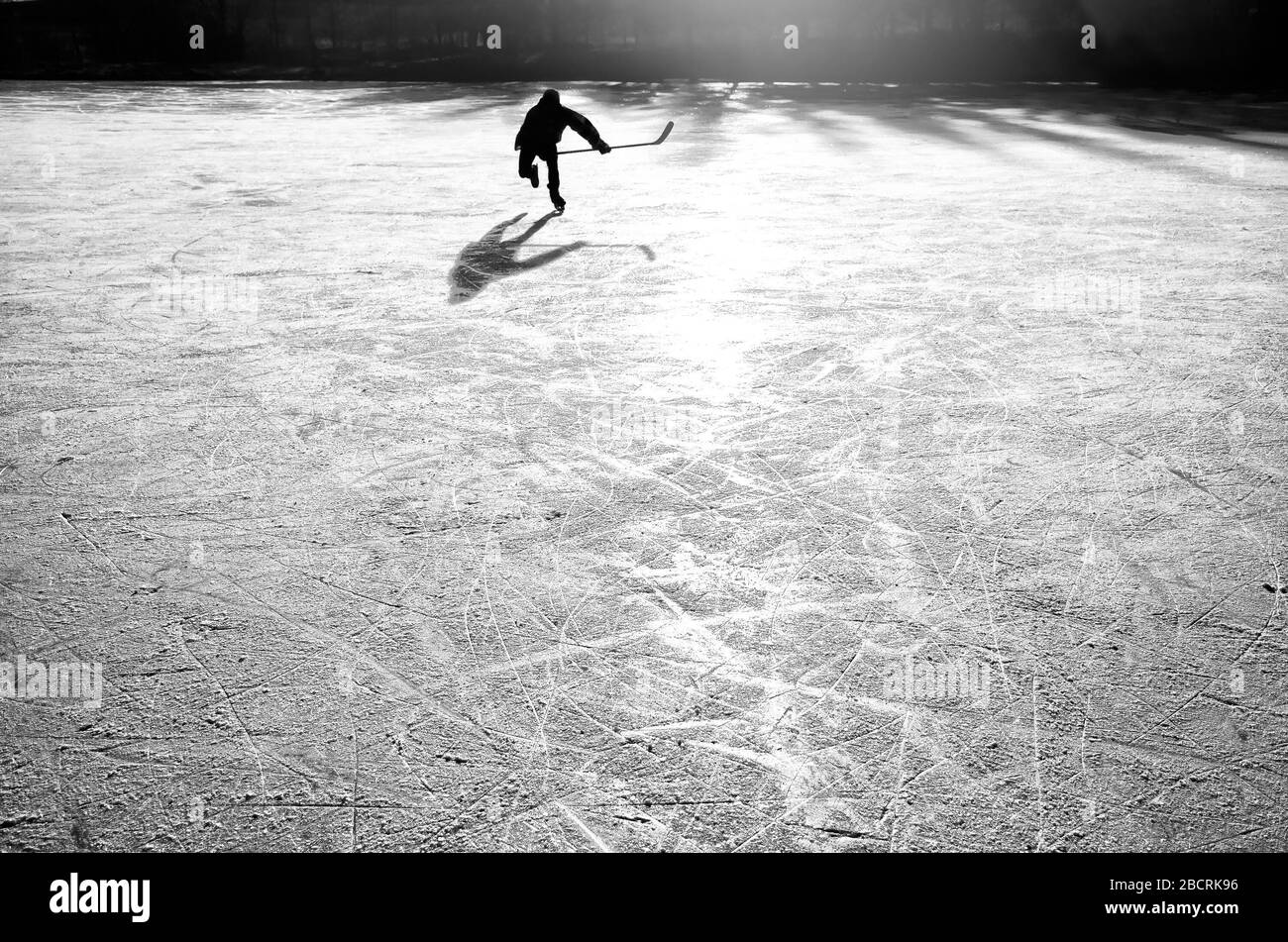 Silhouette di un giovane giocatore di hockey che si diverte sul ghiaccio naturale. Carta da parati originale, sportiva, invernale Foto Stock