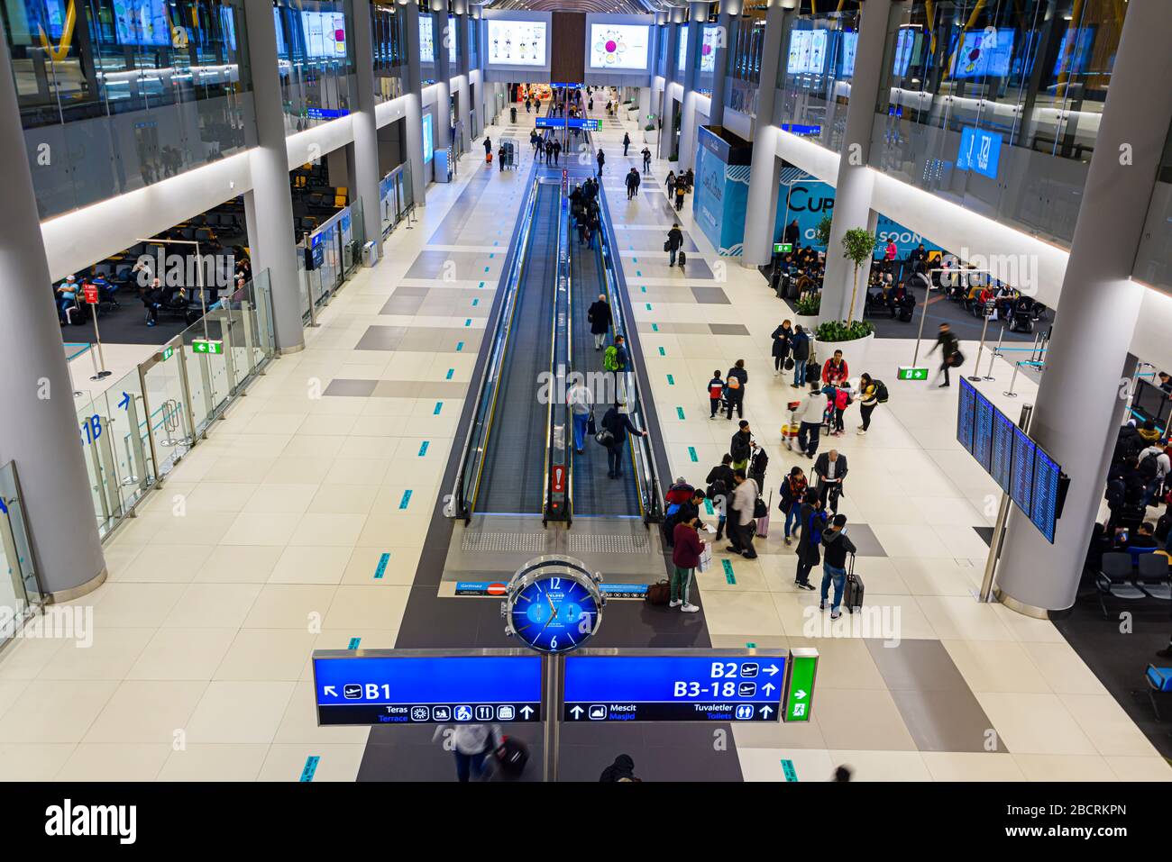 Passeggeri in viaggio lungo un lungo corridoio all'aeroporto di Istanbul (IST), Turchia Foto Stock