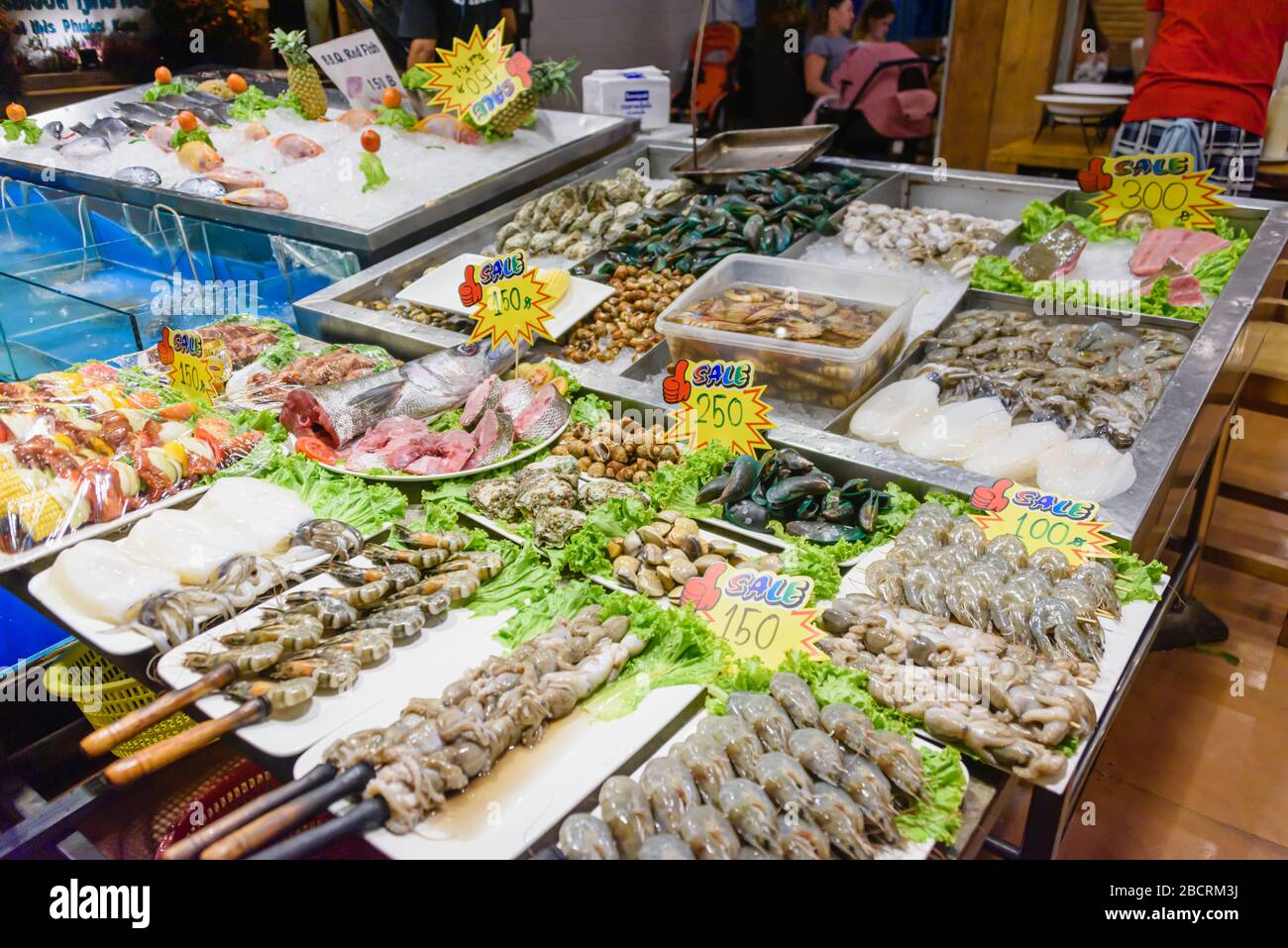 Crostacei compresi gamberi, vongole, granchi e calamari, insieme ai pesci in vendita presso una bancarella di mercato Wet Fishmonger, Kata Beach, Phuket, Thailandia Foto Stock