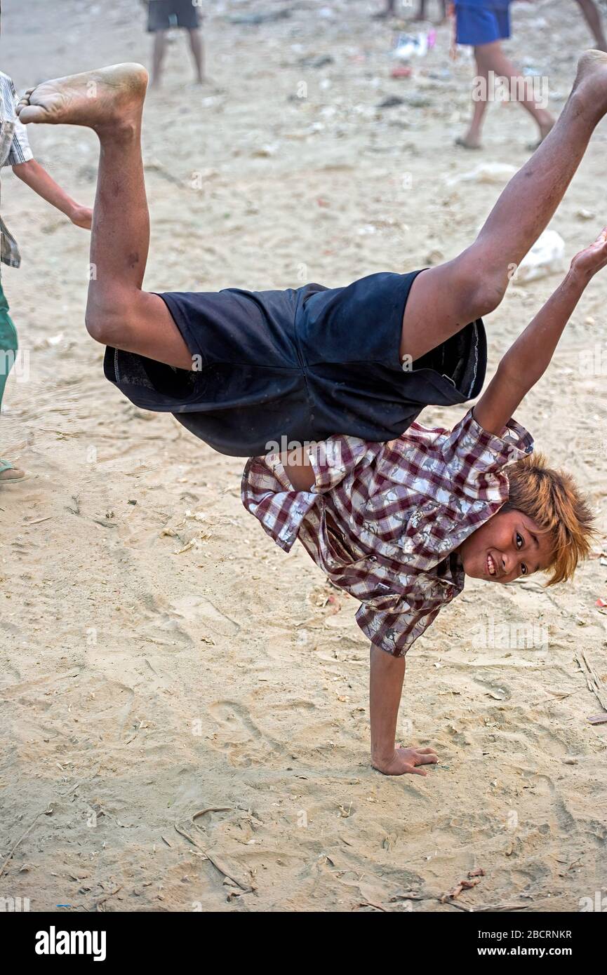 Bambini che giocano e fanno le ruote / cavalletti sulle rive del fiume Ayeyarwaddy in Myanmar (Birmania) Foto Stock